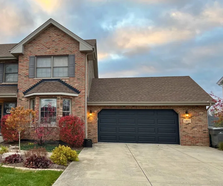 Black garage door installed by World of Doors on a large brick home