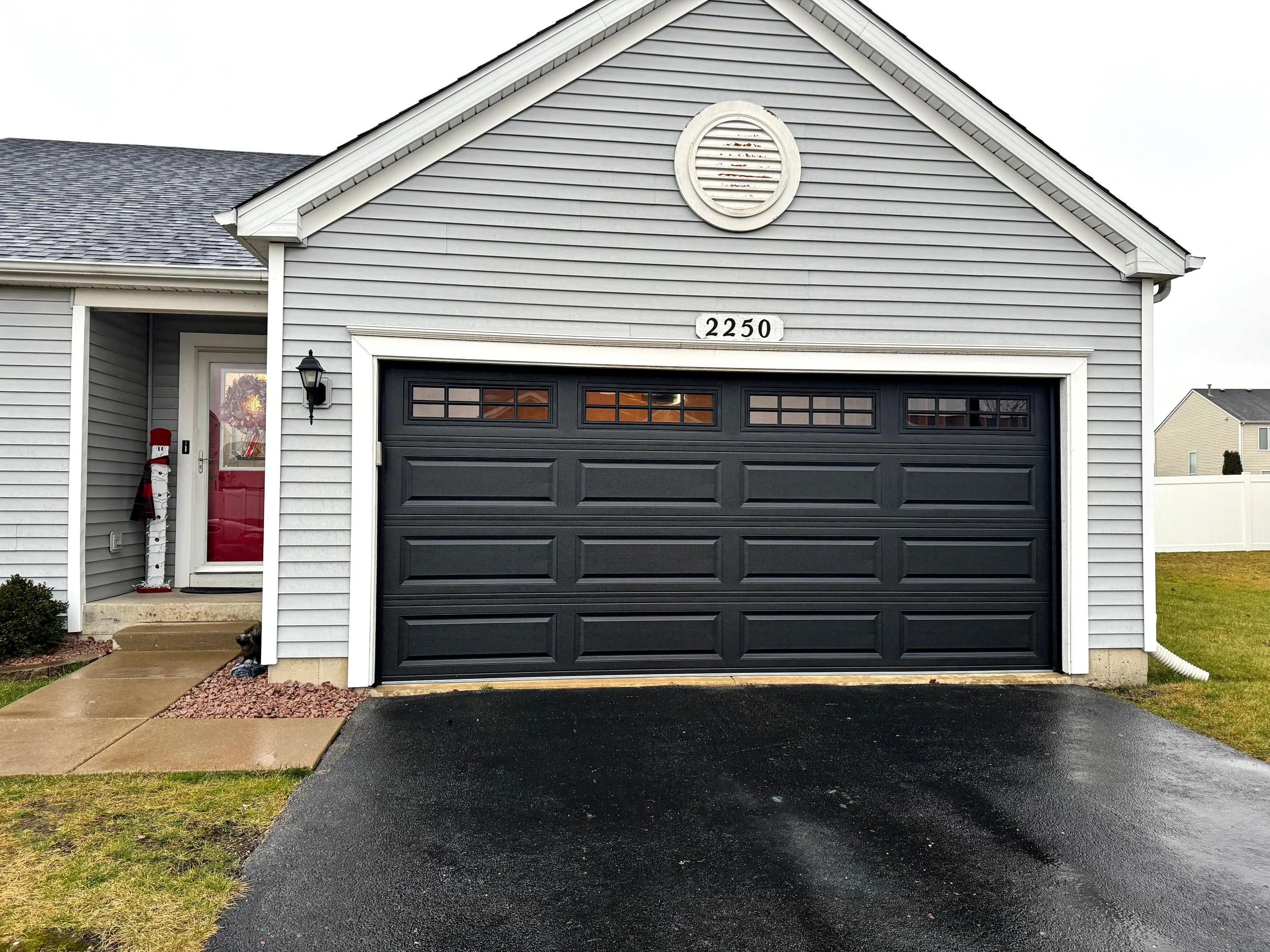 Black classic steel garage door with raised panels and a top row of square windows