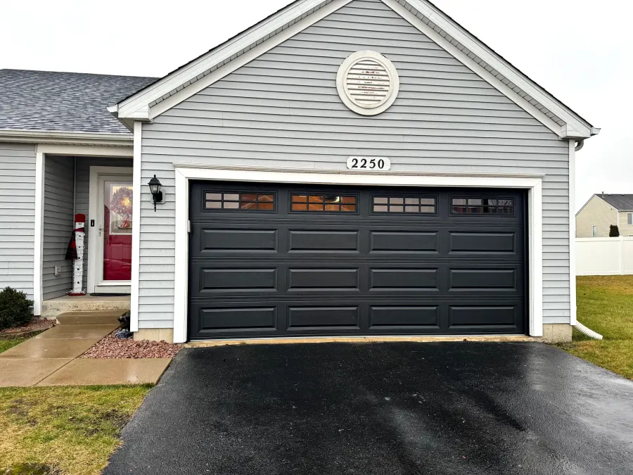 Black classic steel garage door with raised panels and a top row of square windows