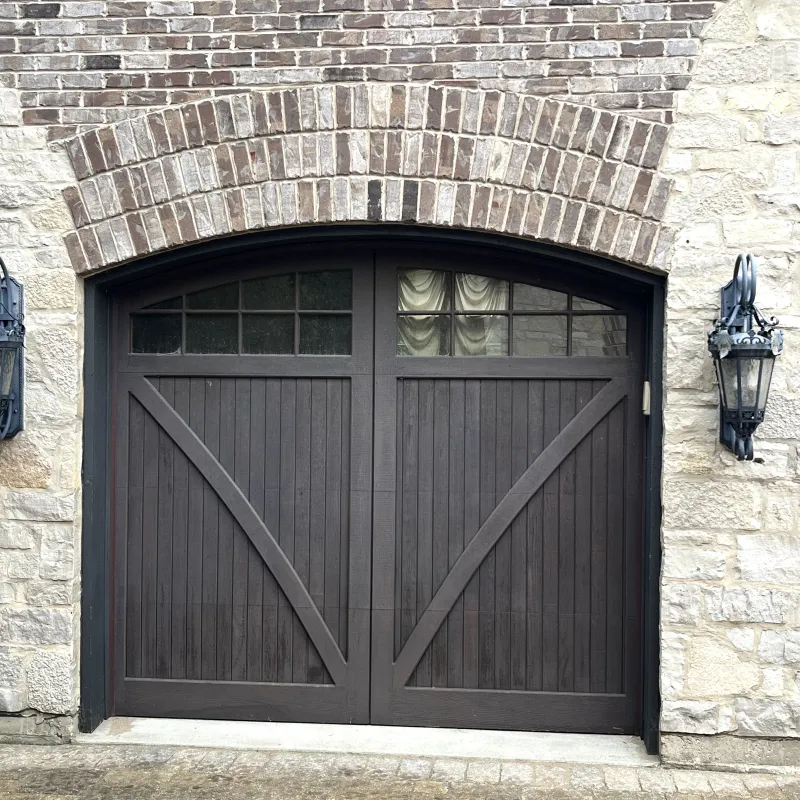 Carriage-style garage door with arched windows on brick