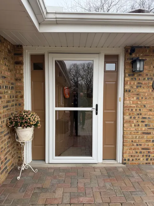White storm door with sidelights on a brick ranch home