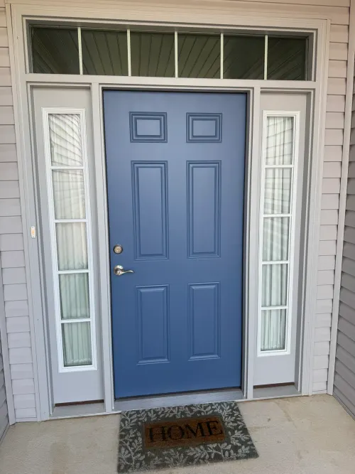 Blue six-panel entry door with sidelights and a transom window