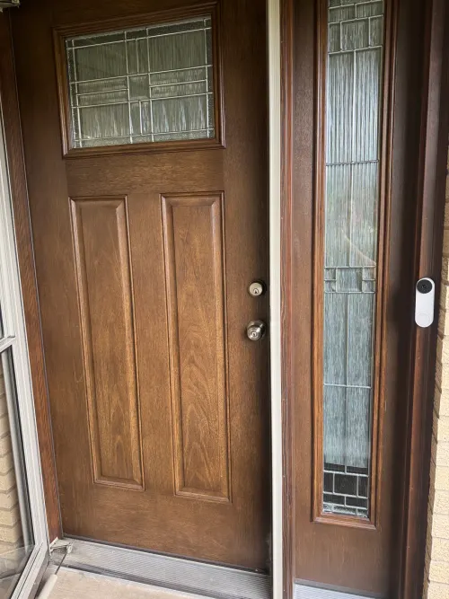 Dark wood Craftsman entry door with a tall decorative glass sidelight
