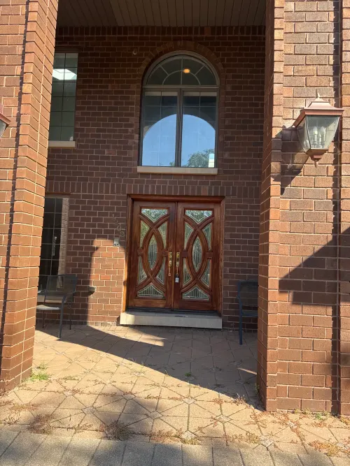 Dark wood double entry doors with arched transom on red-brick