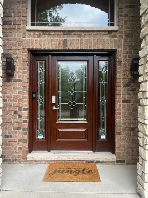 Dark wood entry door with decorative leaded-glass sidelights