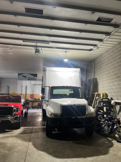 Front view of a white box truck parked in the World of Doors shop