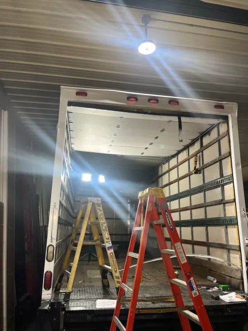 Inside a box truck cargo area mid-install with two ladders set up