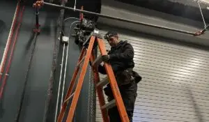 Technician performing commercial door repair on a large industrial garage door.