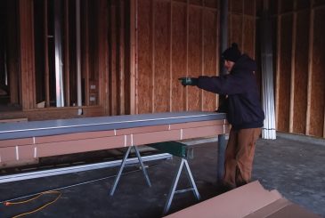A man working on a piece of wood in an unfinished room