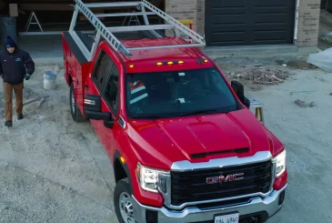 A red gmc truck is parked in front of a garage.