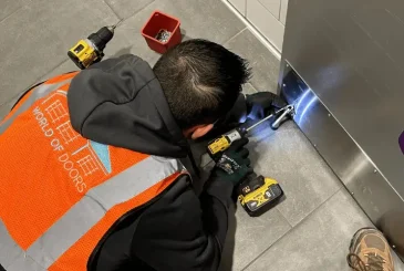 A man adding a kick plate to a commercial overhead door, also suitable for enhancing garage door durability and functionality.