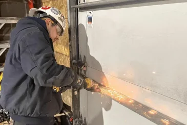 the man is grinding the metal of a garage door