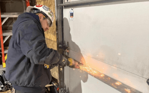 the man is grinding the metal of a garage door