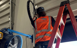 The man wearing the safety vest installing the garage door. Comprehensive garage door maintenance.