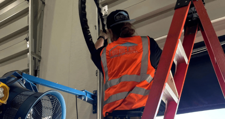 The man wearing the safety vest installing the garage door. Comprehensive garage door maintenance.