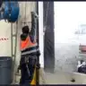 Technician in safety vest using tools to repair a damaged garage door in an industrial warehouse