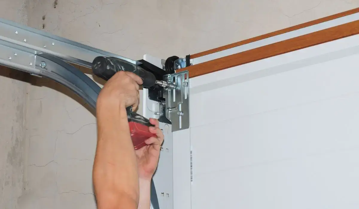 Technician using power drill to repair garage door system track and bracket causing loud banging noise.