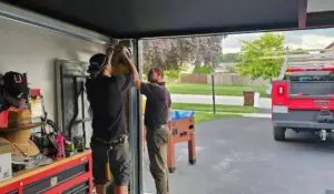 Technicians adjusting the garage door opener during a repair session.